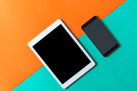 tablet and smart phone on orange green paper backgroundの写真素材