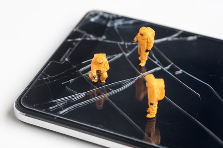 miniature people are inspect  the fracture on smartphone screenの写真素材
