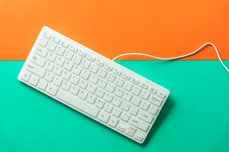 white computer keyboard on orange green backgroundの写真素材