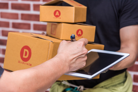receiver sign on tablet when receive a package box from delivery manの写真素材