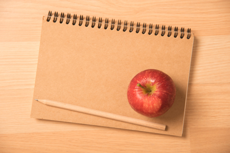 red apple on notebook with a pencilの写真素材