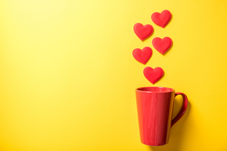 red coffee cup with smoke heart on yellow paper backgroundの写真素材