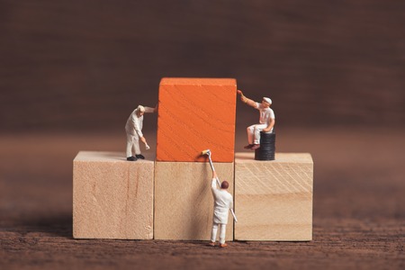 miniature people worker painting wood cube building block , wood backgroundの写真素材