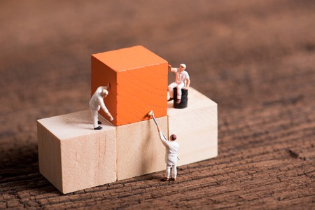 miniature people worker painting wood cube building block , wood backgroundの写真素材