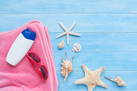 sunglasses , towel and sunscreen on light blue wood plank floor for summer vacation time backgroundの写真素材