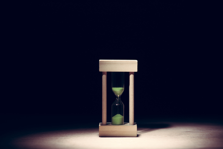 sand glass on wood floor ,  dark background lighted with snootの写真素材