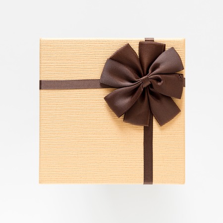 light brown giftbox with brown bow strip on white background , top viewの写真素材