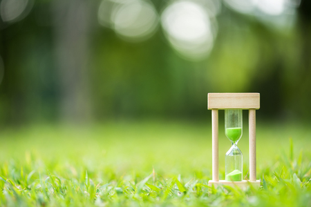 hourglass on green grass field , spring timeの写真素材