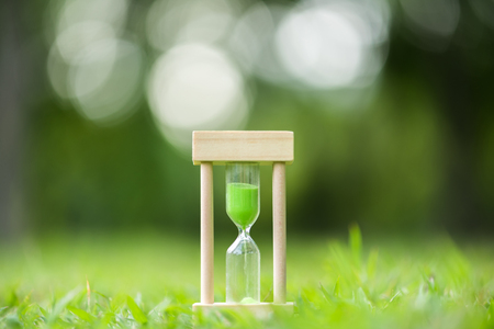 hourglass on green grass field , spring timeの写真素材