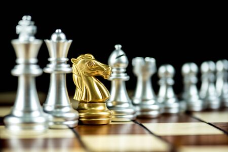 gold knight chess in rows of silver chess pieces on a chessboard, spy strategy concept