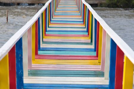 colorful rainbow wood bridge into the sea with blue sky backgroundの写真素材