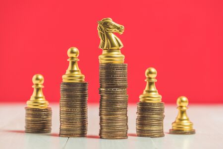 chess on stack of money coins and red background.