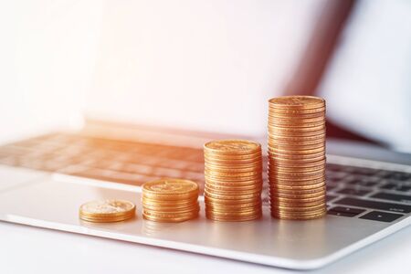 stack of money coins on laptop computer background.