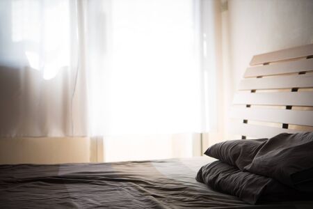 silhouette detail of bed in bed room from light through white curtain