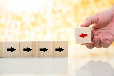 man hand pick up red arrow wood cube from rows of black arrow wood cube