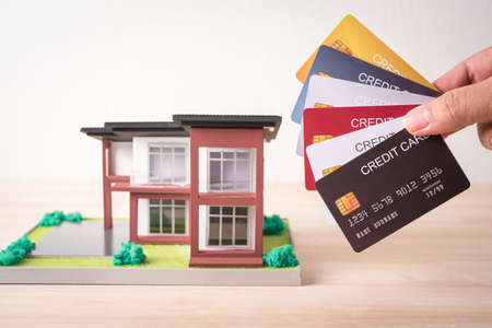 man hand holding credit card and house modelの写真素材