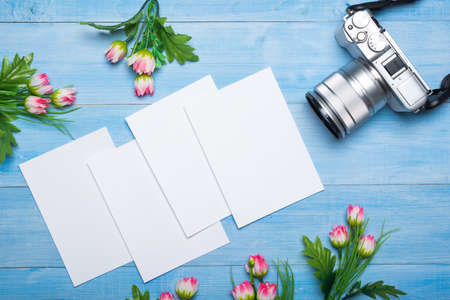 empty photo frames with camera on light blue wooden background