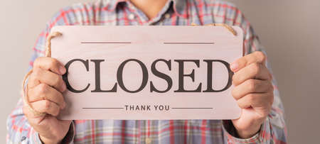 man holding closed sign board