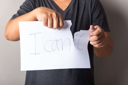 man hand torn the letter t of the written word I can't paper sheet , motivation concept