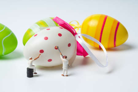 miniature people painting colorful patterns on  easter eggsの写真素材
