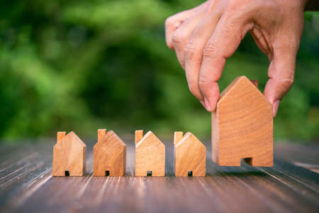 row of wood house mogel on wooden table with green natural leaves backgroundの写真素材