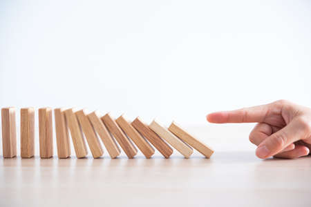 woman hand start wooden block tower stack crash or fall domino  ,financial business and risk managementの写真素材
