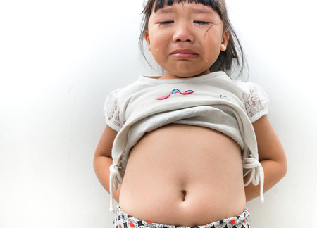 asian little girl cry after show her stomachの写真素材