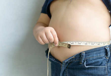 Fat boy measuring his belly with measurement tape