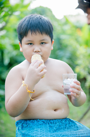 cute fat boy with bread on nature backgroundの写真素材