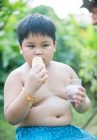 cute fat boy with bread on nature backgroundの写真素材