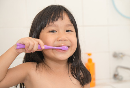 cute asian girl brushing teeth in bathroomの写真素材