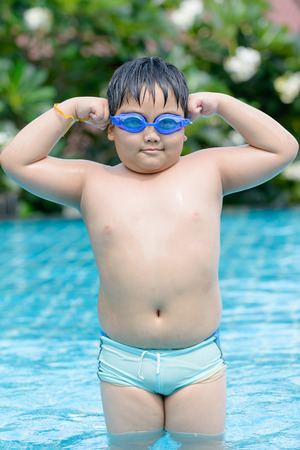asian fat boy showing him muscle in swimming pool.の写真素材