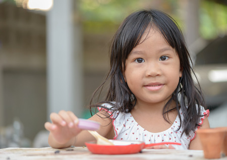 Smiling little girl plays cook on the tableの写真素材