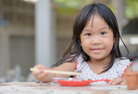 Smiling little girl plays cook on the tableの写真素材