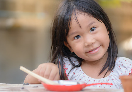 Smiling little girl plays cook on the tablesの写真素材