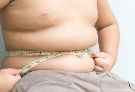 Fat boy measuring belly with measurement tapeの写真素材