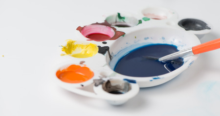 paintbrush on color dish in white backgroundの写真素材