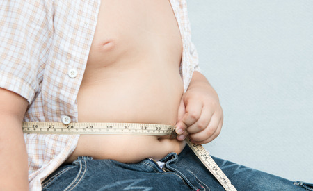 fat boy measuring his obese on gray backgroundの写真素材