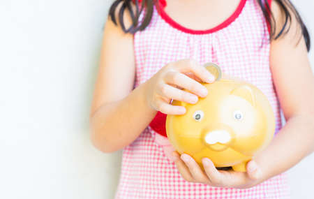 little girl hand put coin to piggy bankの写真素材