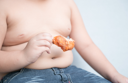 fried chicken in fat boy hand on gray backgroundの写真素材
