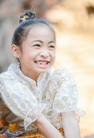 Cute little girl wearing typical thai dress on temple backgroundの写真素材