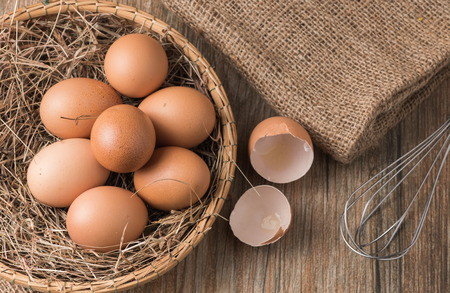 fresh egg in basket on wood backgroundの写真素材