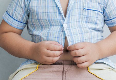 fat boy overweight. Tight shirt on gray backgroundの写真素材