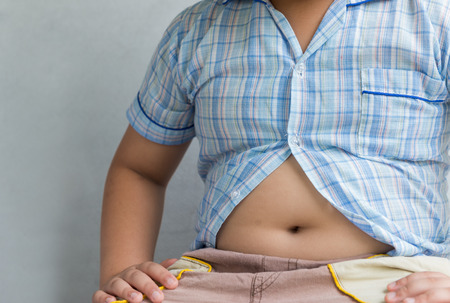 fat boy overweight. Tight shirt on gray backgroundの写真素材