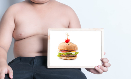 fat boy show hamburger picture on whiteboard, concept is Hamburgers (junk food) cause obesity.の写真素材