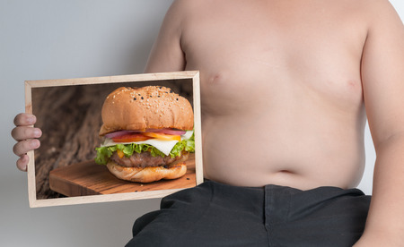 fat boy show hamburger picture on chalkboard, concept is Hamburgers (junk food) cause obesityの写真素材