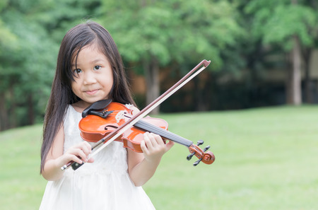 cute asian girl play violin in park or nature background.の写真素材