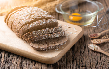 Homemade Cereal bread with raw egg on old wooden background.