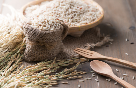 brown Jasmine rice in sack on wood background, healthy food and diet conceptの写真素材