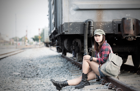 Hipster young girl waiting train on railway background and vintage tone, concept travel and leisure.の写真素材